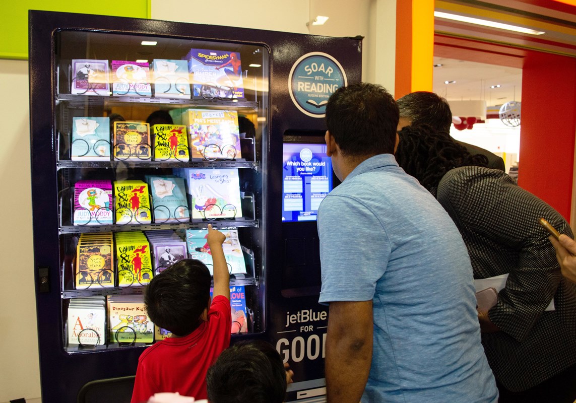 A child selects a book to take home from the JetBlue vending machine.
