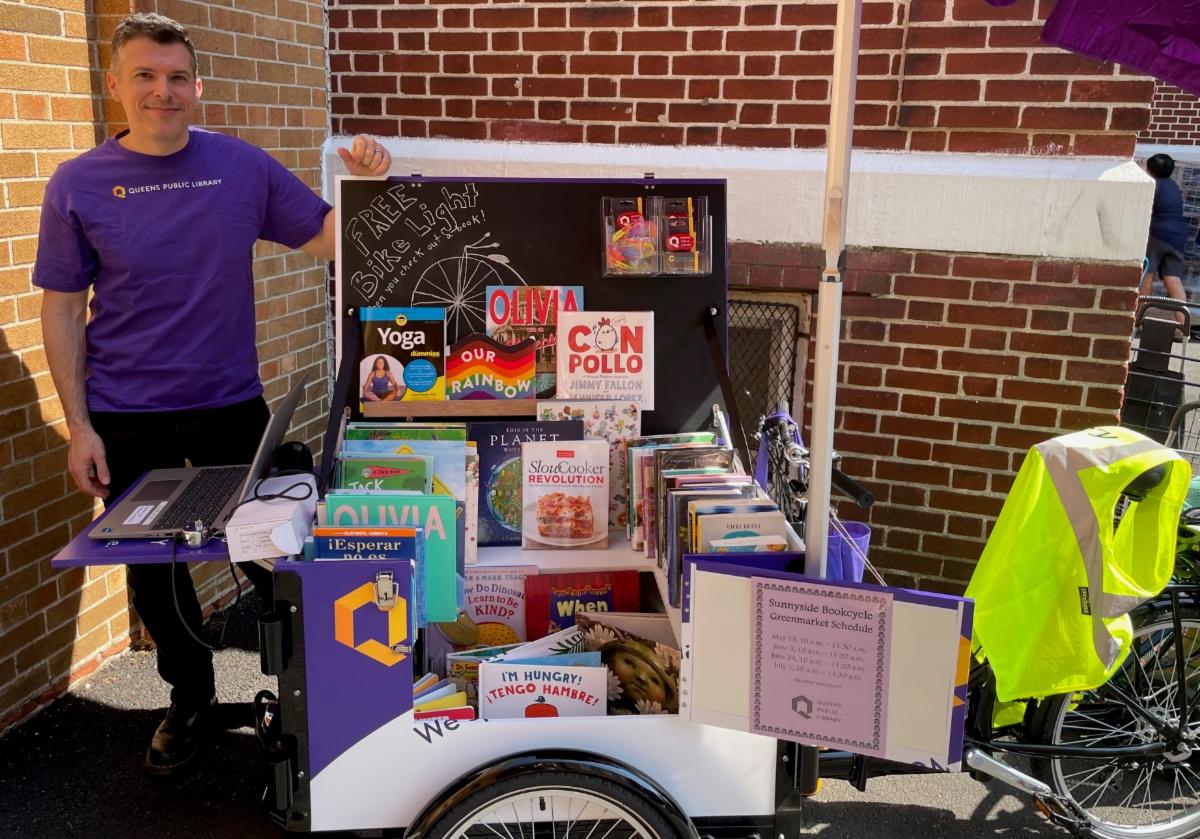 Sunnyside Library Manager Joe Schiavone with the QPL Bookbike at St. Teresa's Food Pantry in Woodside.
